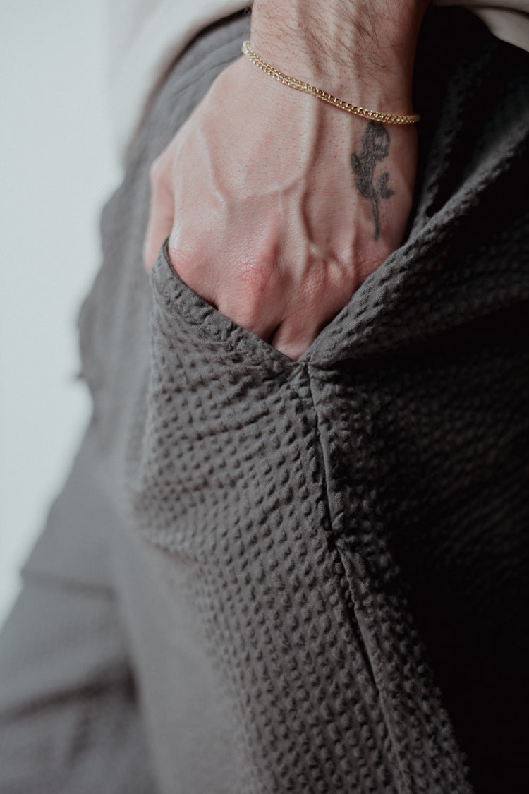 Person wearing a versatile gold recycled chain on a textured grey sweater with a neutral background