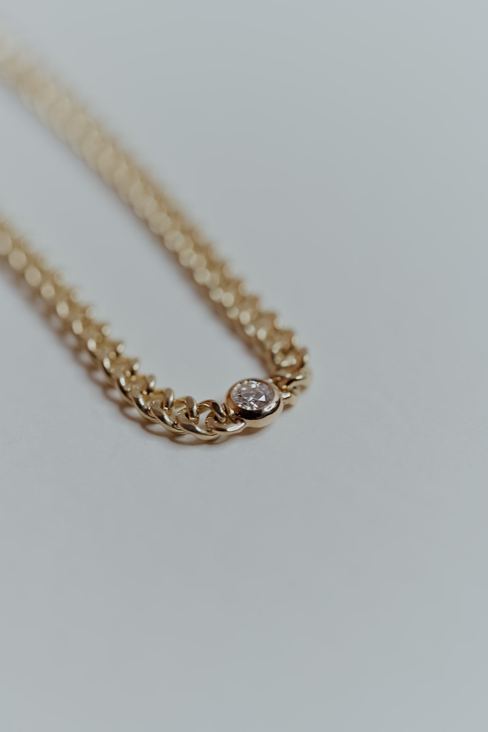 Ethically sourced gold chain bracelet with a recycled round natural diamond on a light gray background