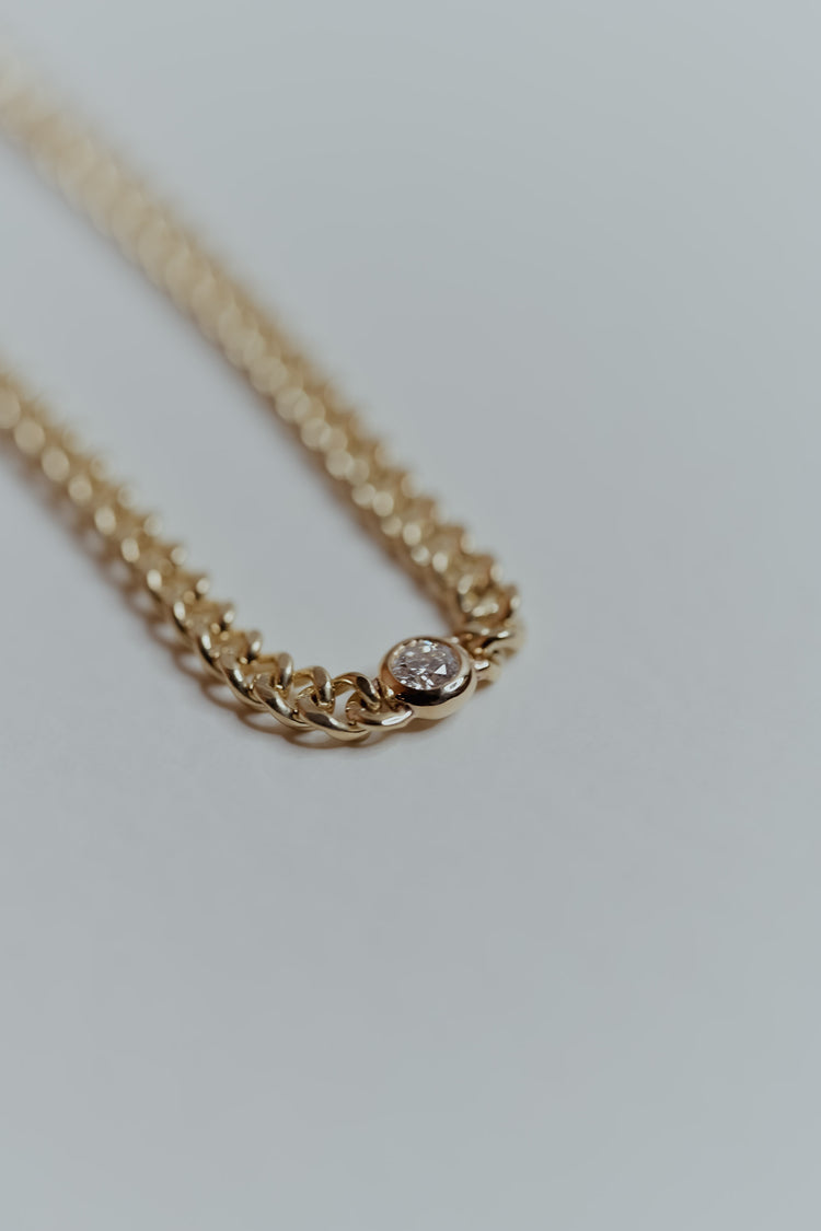 Ethically sourced gold chain bracelet with a recycled round natural diamond on a light gray background