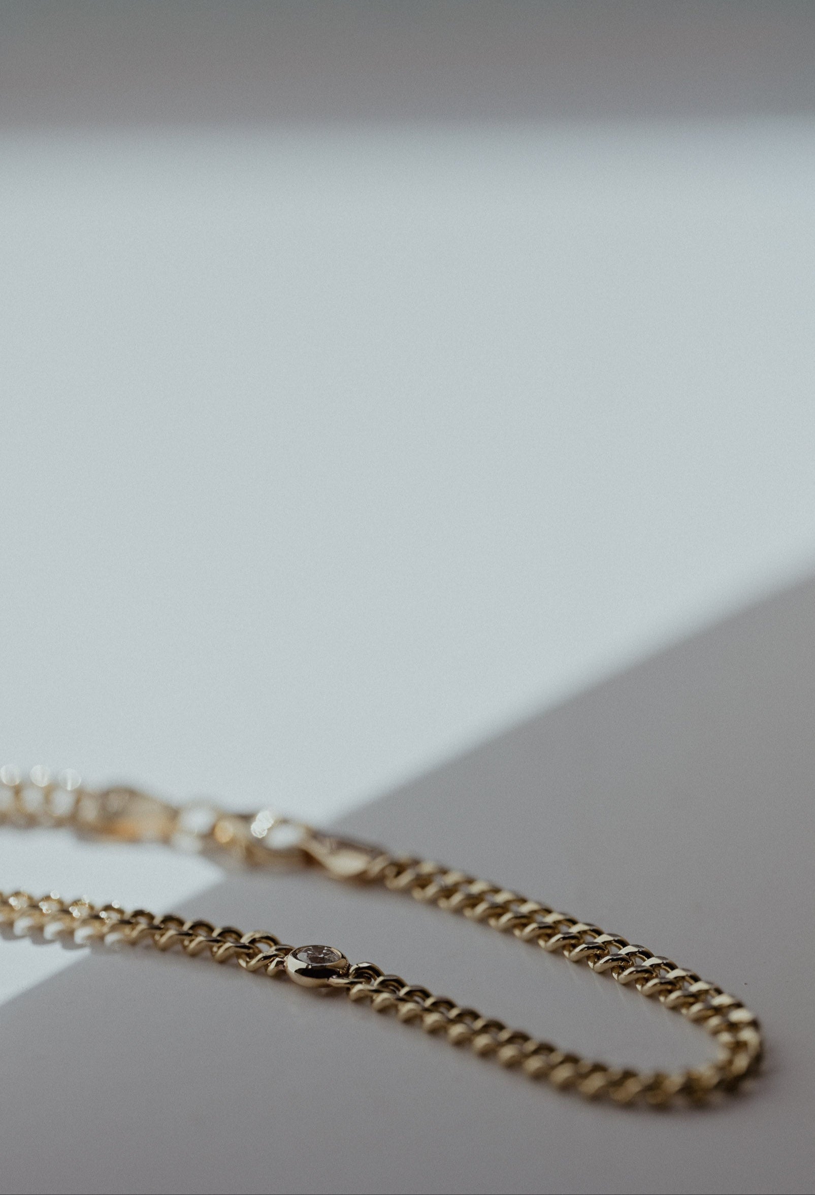 Gold curb chain bracelet with a round natural diamond.