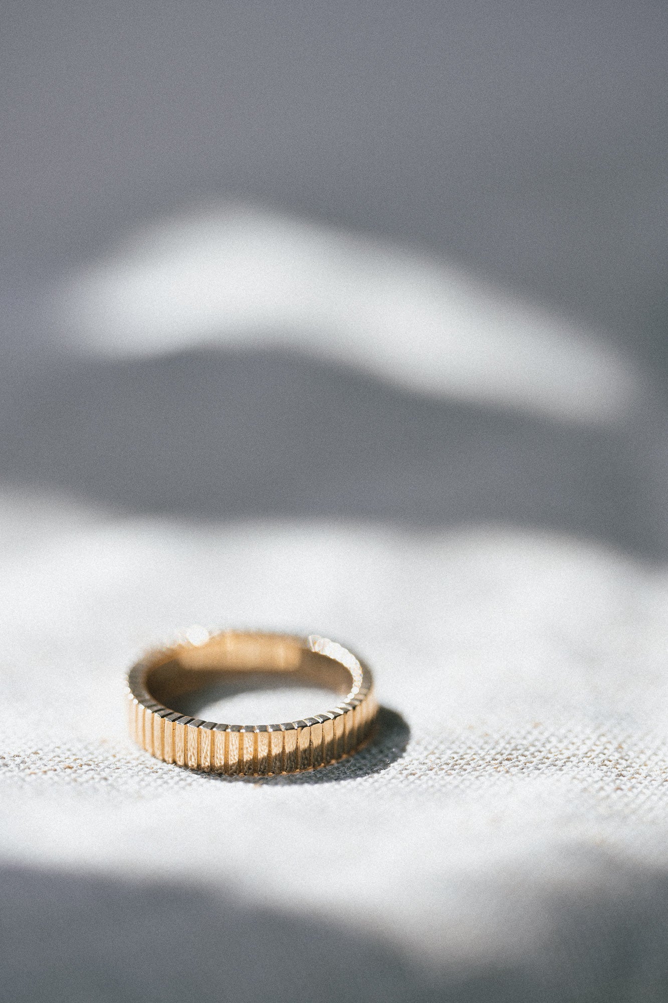 Gold linear ring on a textured surface with soft shadows