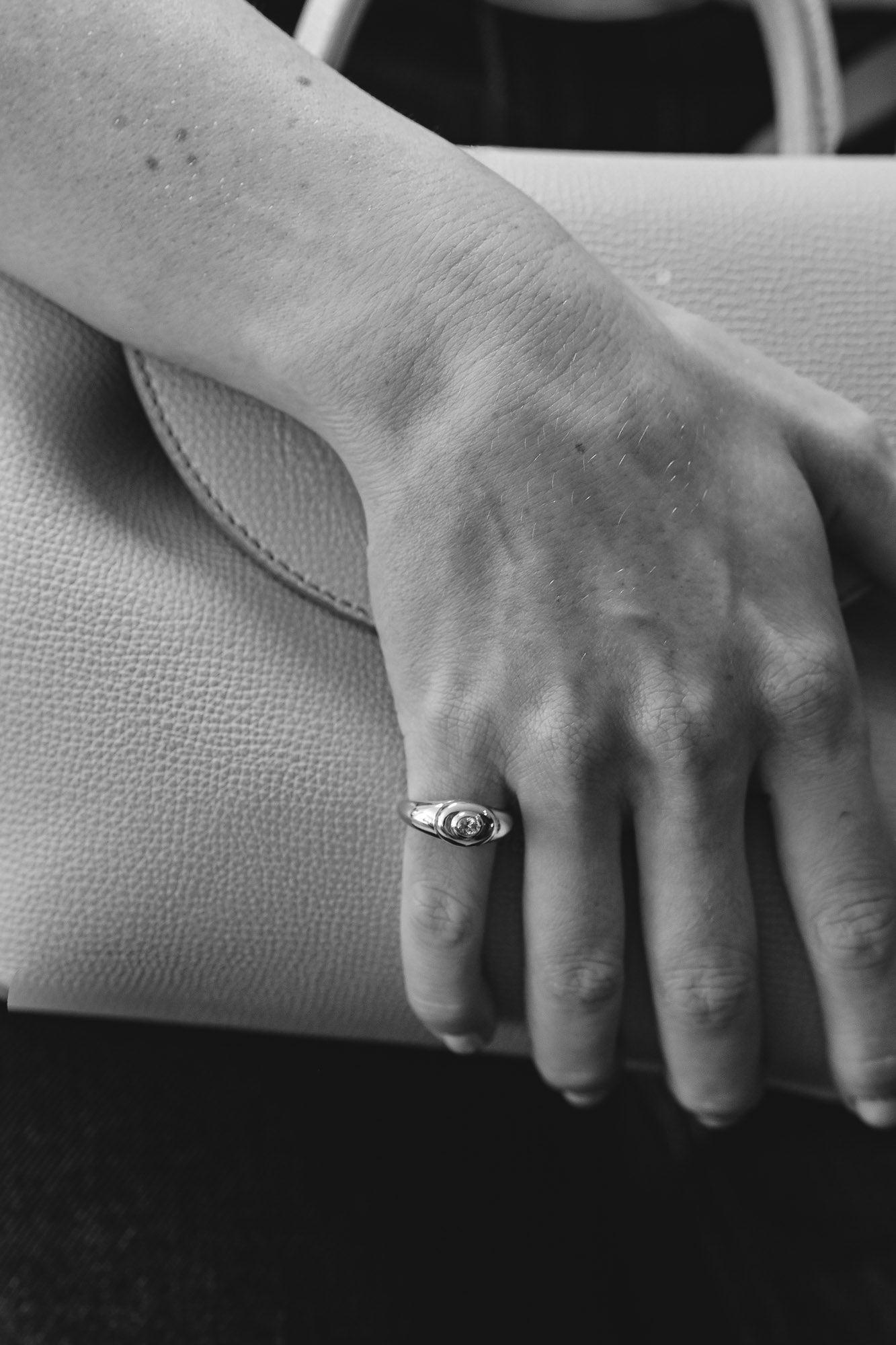 Hand with a signet ring with modern design on a textured surface