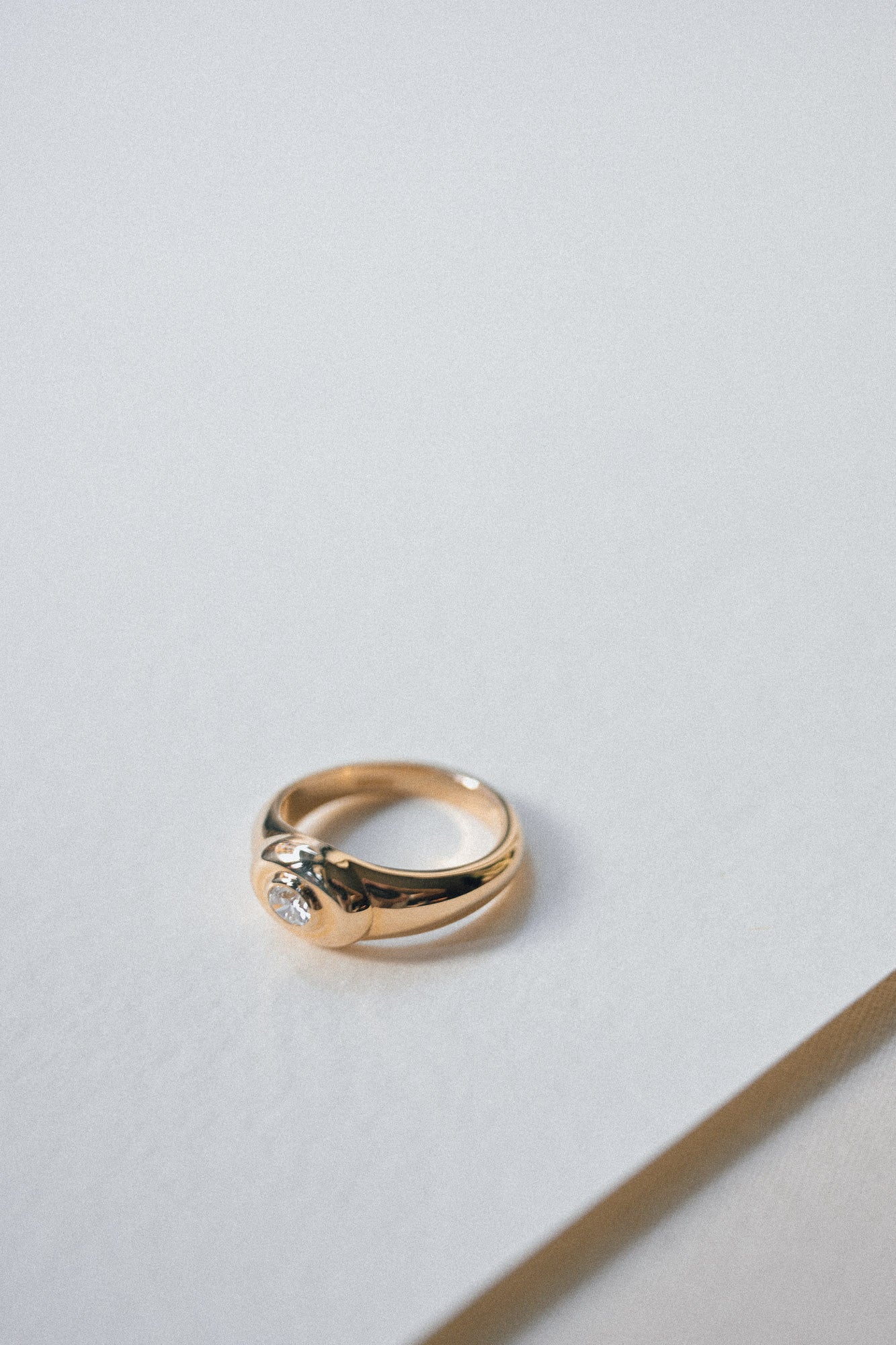 Gold ring with a oval diamond on a light gray background