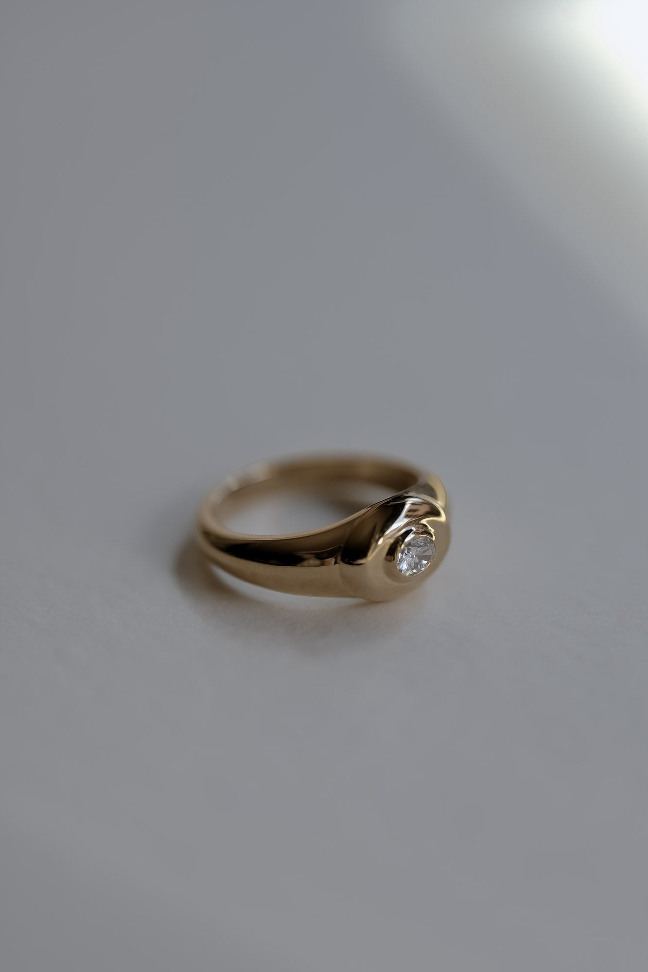 Gold signet ring with a oval diamond on a gray background