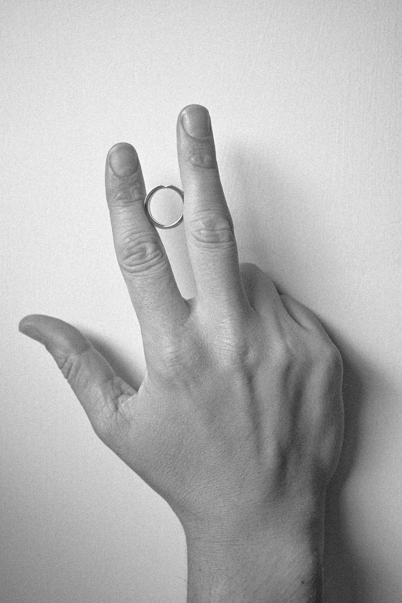 Black and white drawing of a hand with a arrow ring shape on a plain background