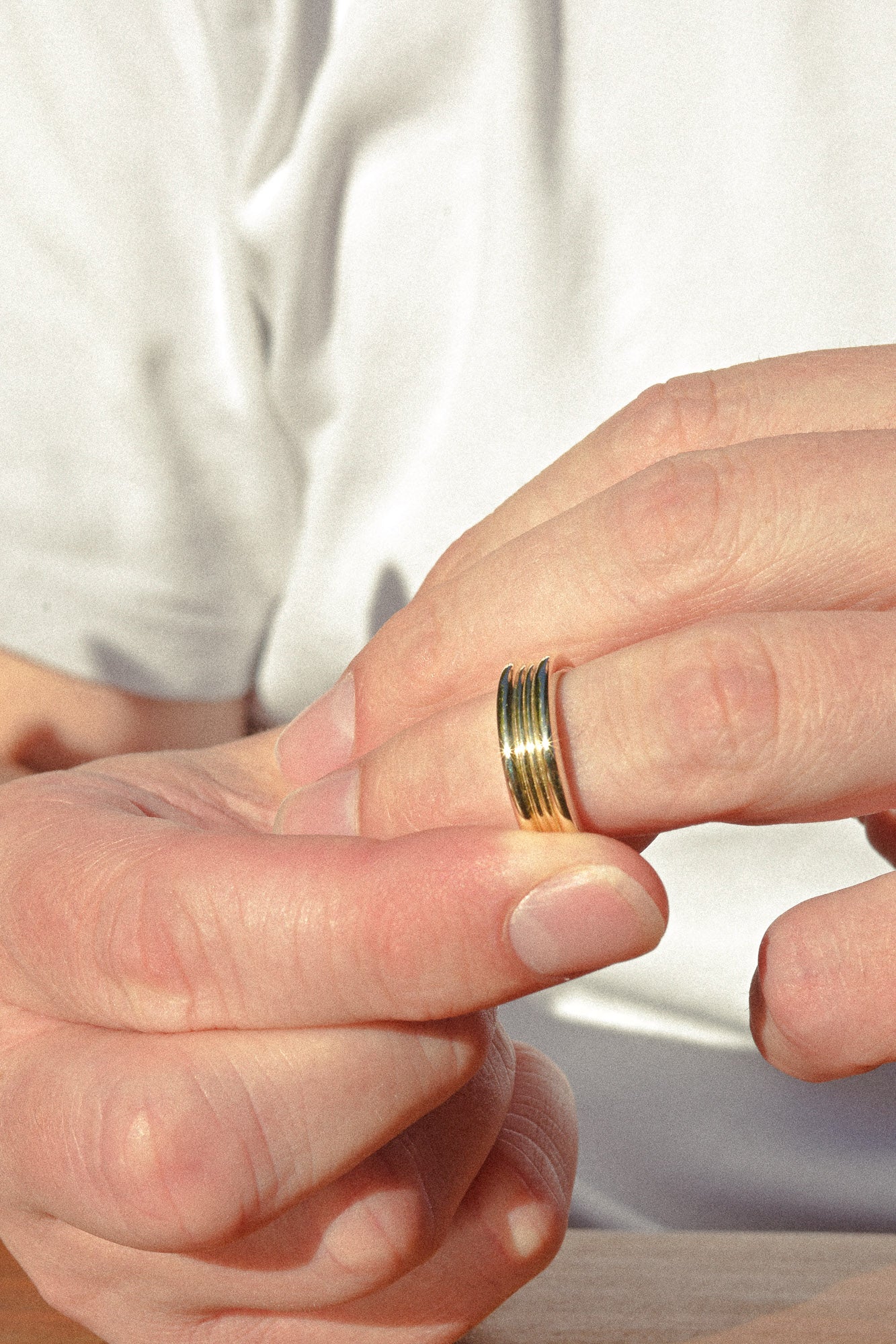Close-up of a hand wearing a gold ring with a blurred background