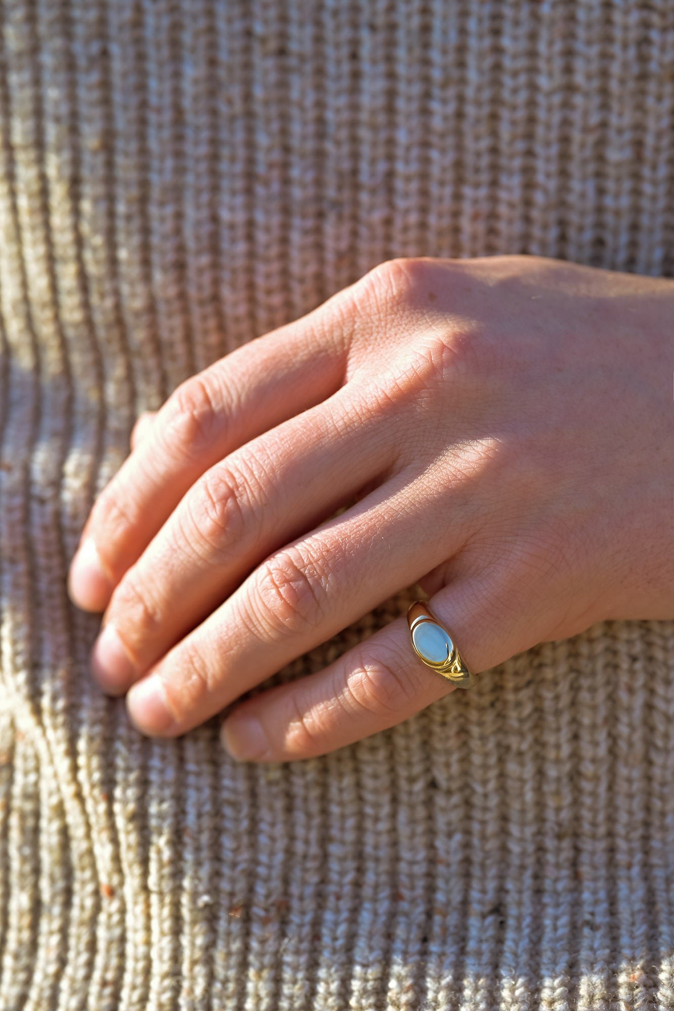 Hand wearing a gold signet ring made of recycled metals 