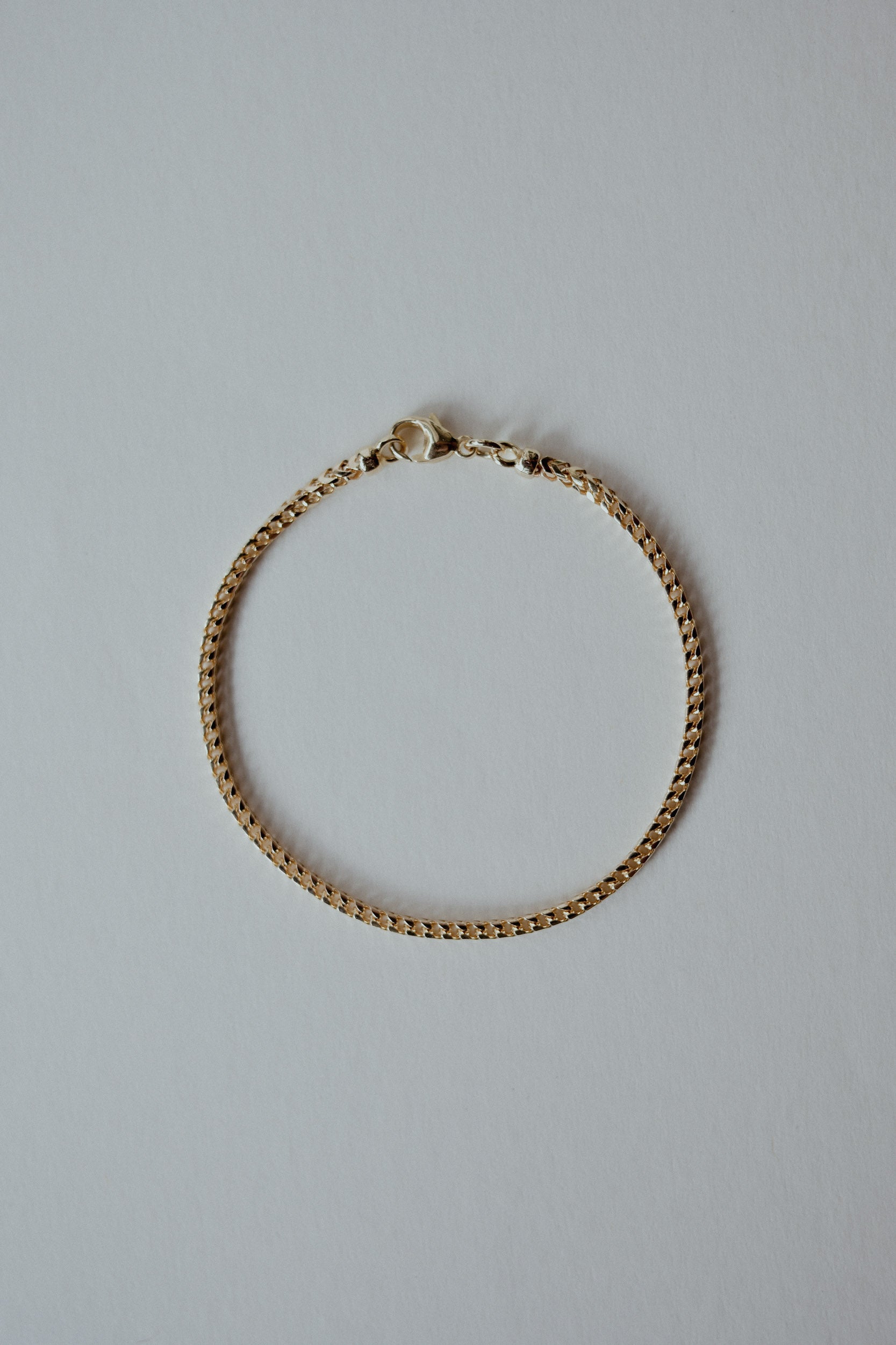 Gold chain bracelet on a light gray background