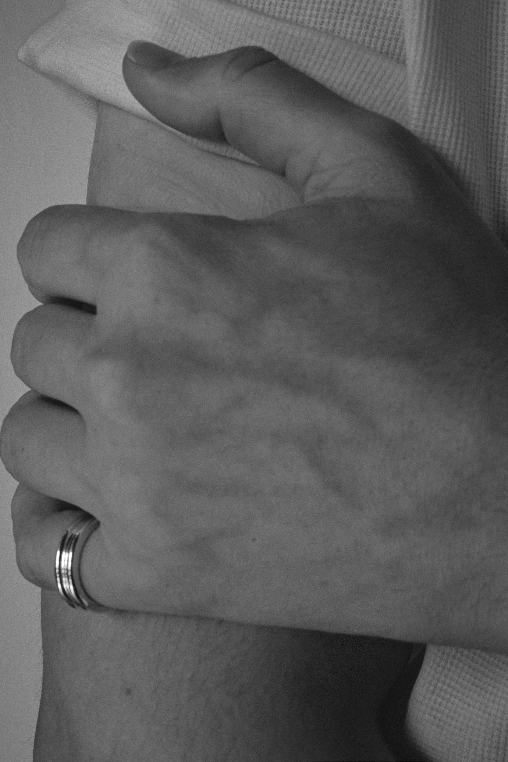 Close-up of a person's hands with a ring, wearing a checkered shirt.