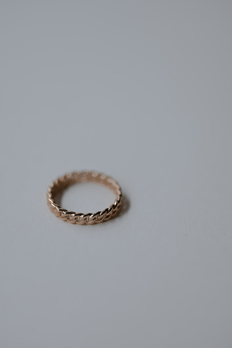 Beautiful gold ring with rope design on a light gray background