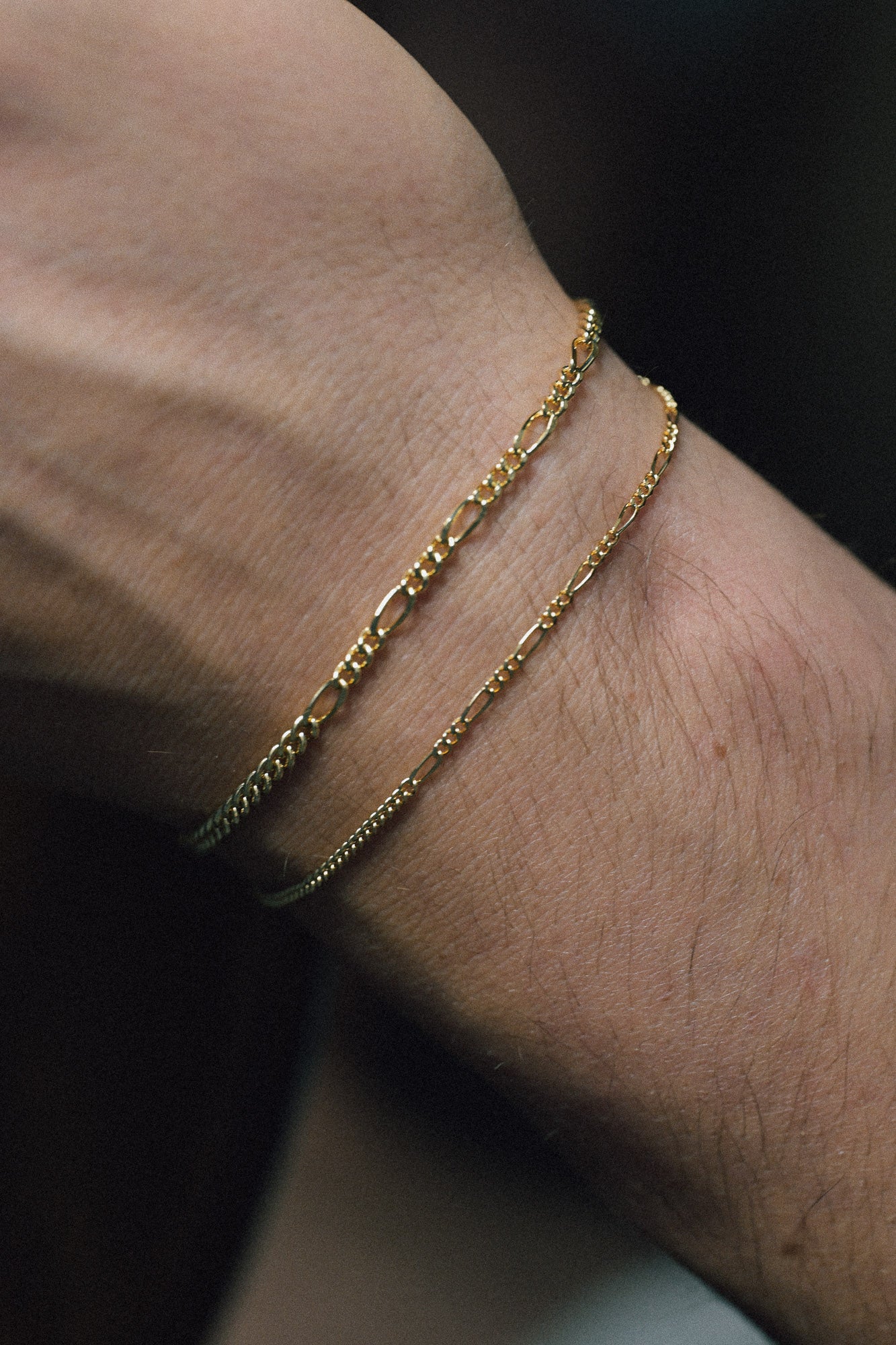 Recycled gold bracelet on a man wrist with a dark background
