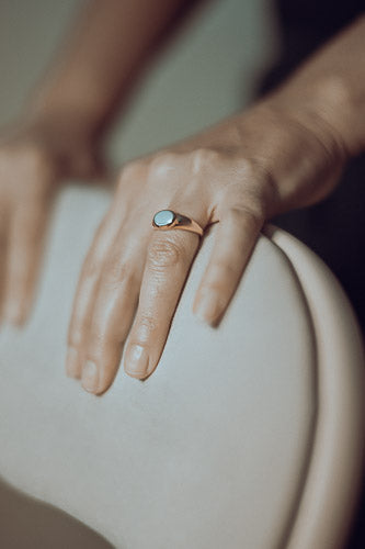 Woman's hand close-up featuring modern signet ring in post-consumer recycled gold 