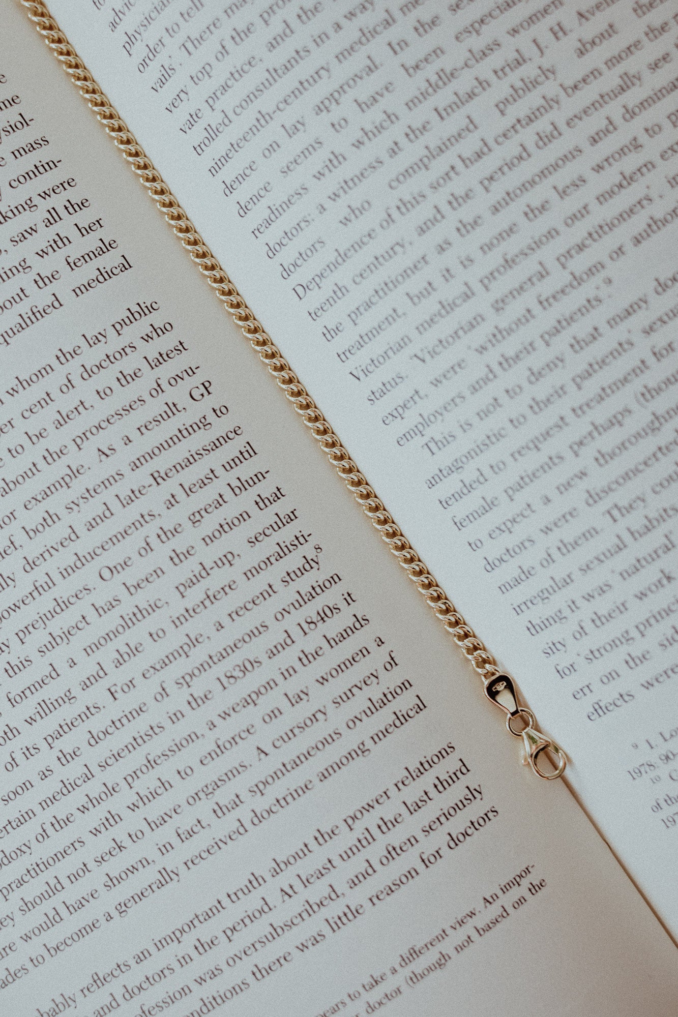 Open book with gold chain bookmark on a white background. Quiet luxury Jewellery made in London. 