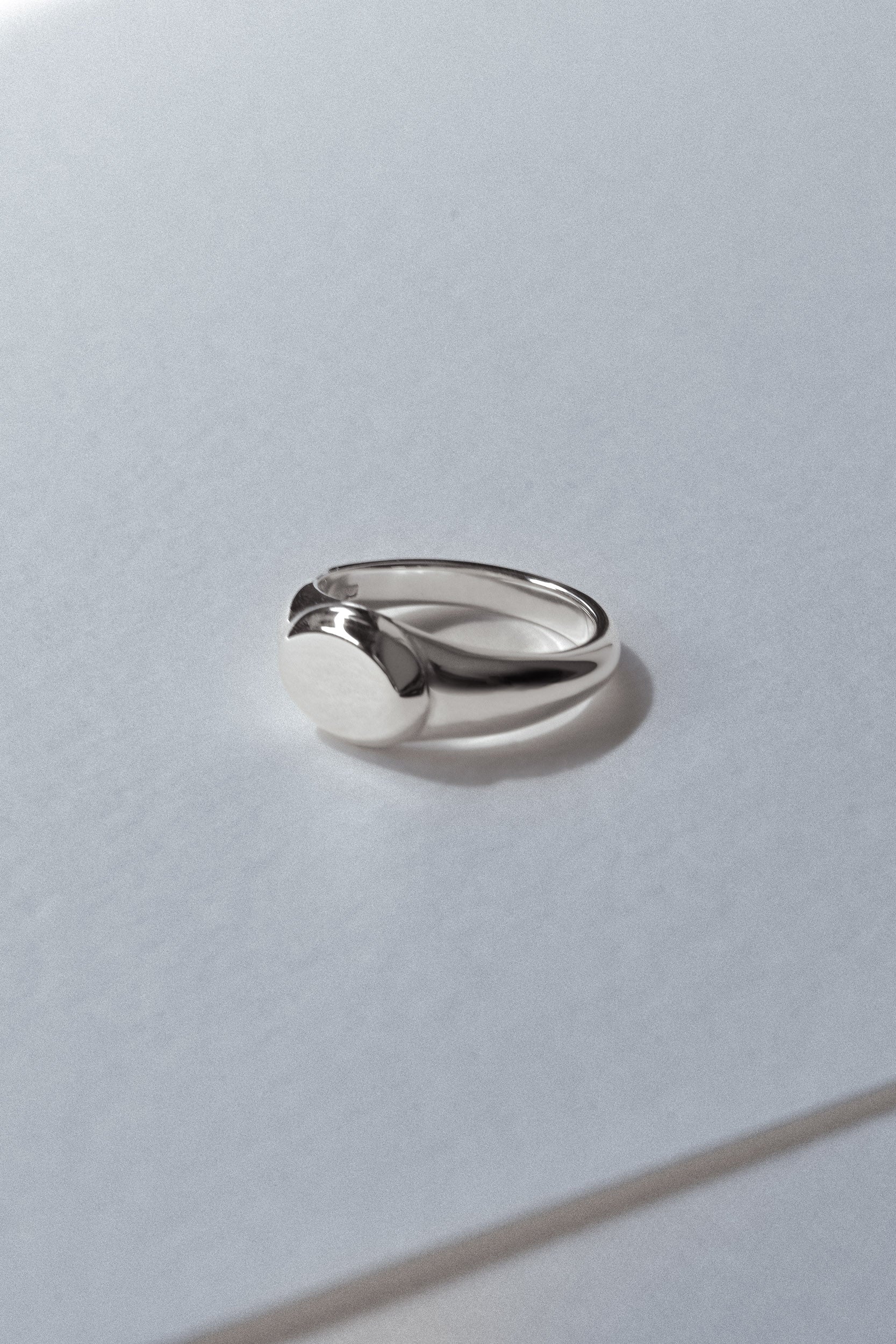 Silver signet ring on a light gray background