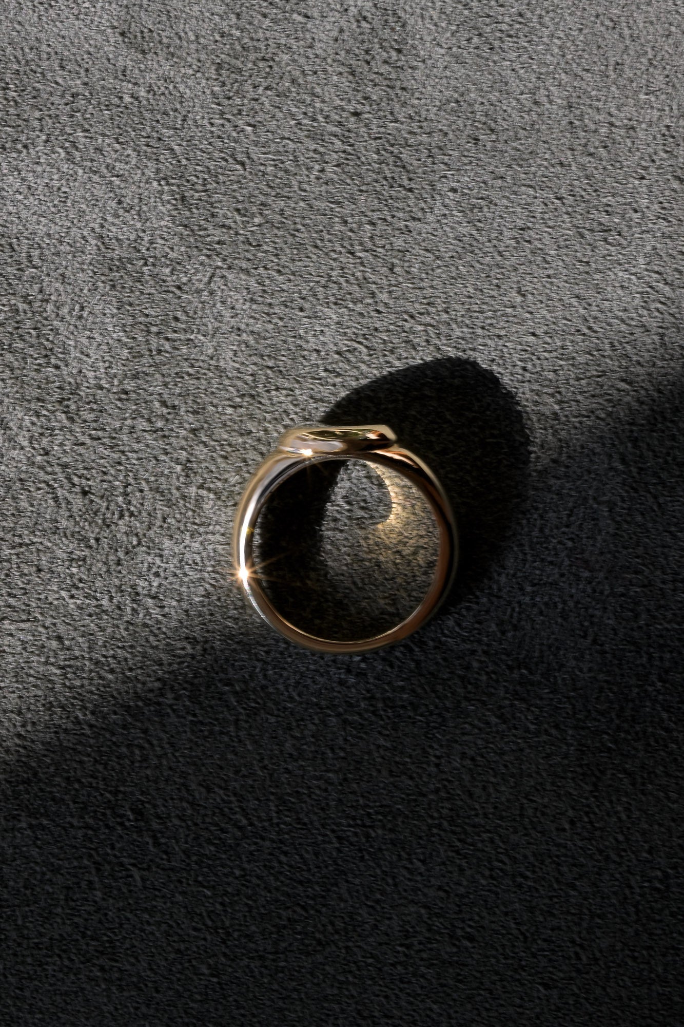 Gold signet ring on a textured green velvet surface showing its unique design 